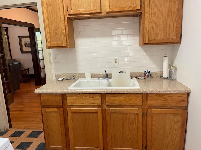 kitchen featuring tasteful backsplash, light countertops, and a sink