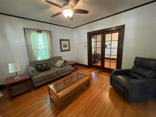 living room featuring light wood-type flooring, a textured ceiling, crown molding, and french doors