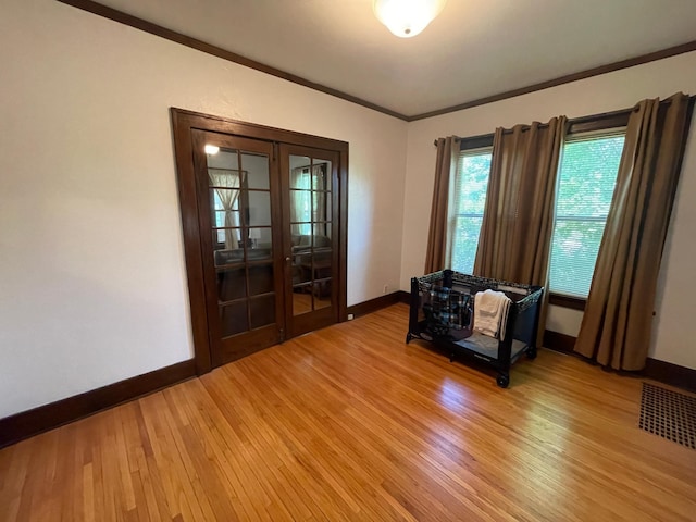 unfurnished room featuring light wood-style floors, baseboards, ornamental molding, and french doors