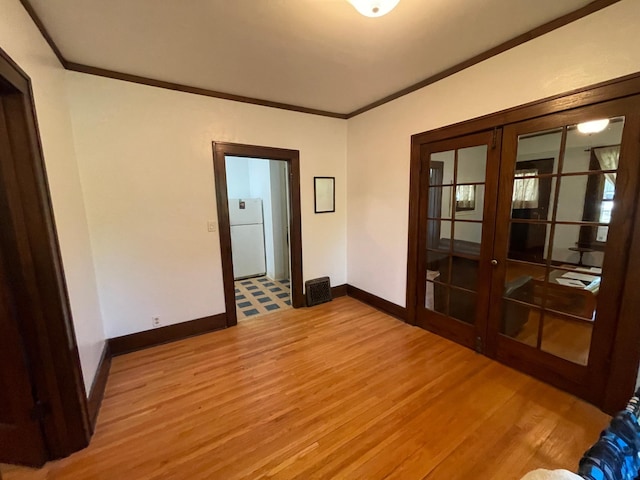 unfurnished room featuring baseboards, ornamental molding, wood finished floors, and french doors