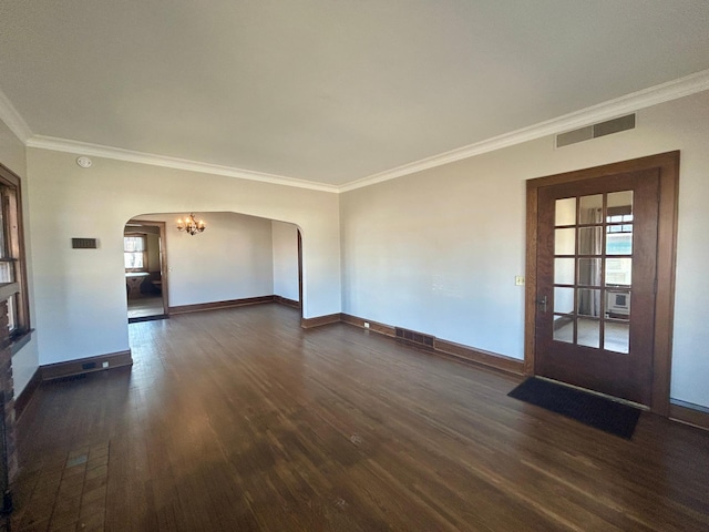 spare room featuring arched walkways, dark wood-style flooring, visible vents, baseboards, and crown molding