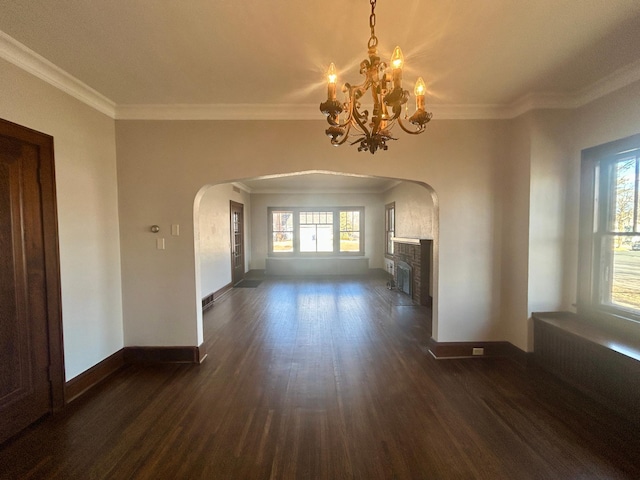 unfurnished living room featuring dark wood-style floors, a fireplace, arched walkways, and crown molding