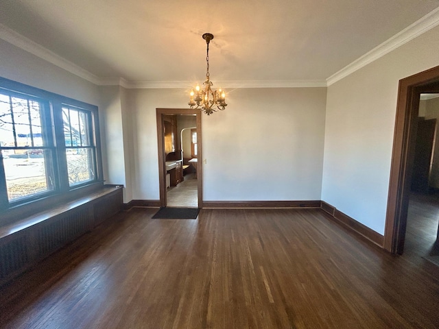 empty room featuring ornamental molding, a notable chandelier, dark wood finished floors, and baseboards