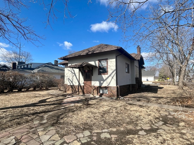 back of house featuring stucco siding, a chimney, and brick siding