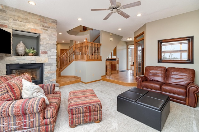 carpeted living area with stairs, a stone fireplace, recessed lighting, and baseboards