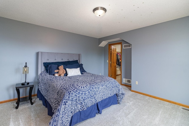 carpeted bedroom featuring baseboards, visible vents, arched walkways, and a textured ceiling