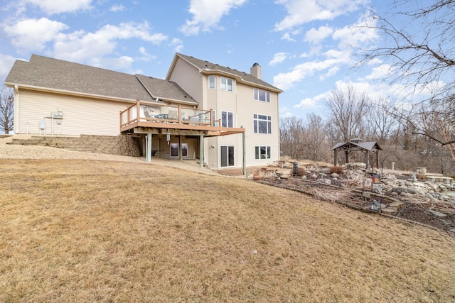 back of property featuring a yard, a chimney, and a wooden deck