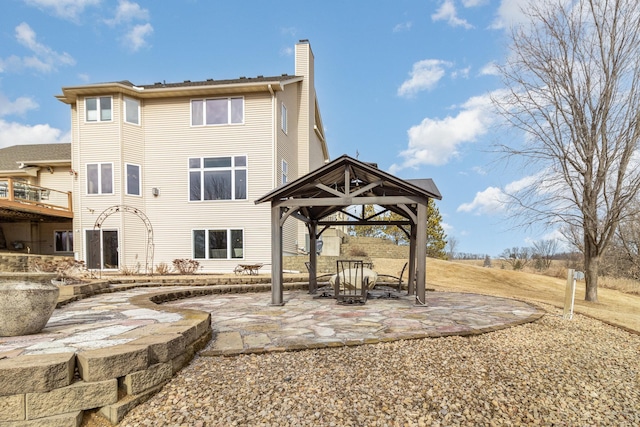 rear view of house featuring a patio area, a chimney, and a gazebo