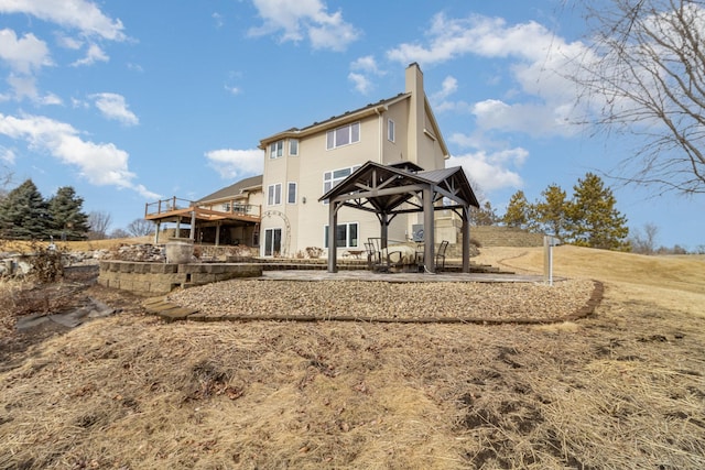 back of property with a chimney and a gazebo