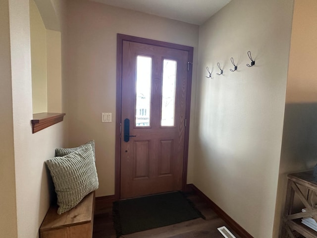 doorway to outside with arched walkways, wood finished floors, visible vents, and baseboards