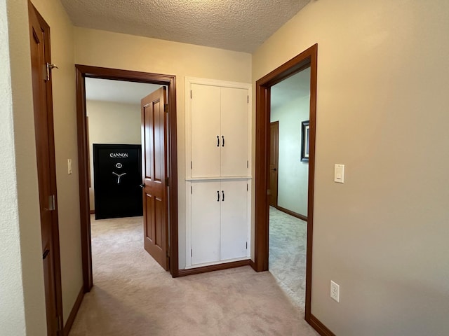 corridor with baseboards, light carpet, and a textured ceiling