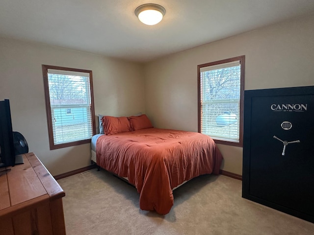 bedroom featuring multiple windows, light colored carpet, and baseboards