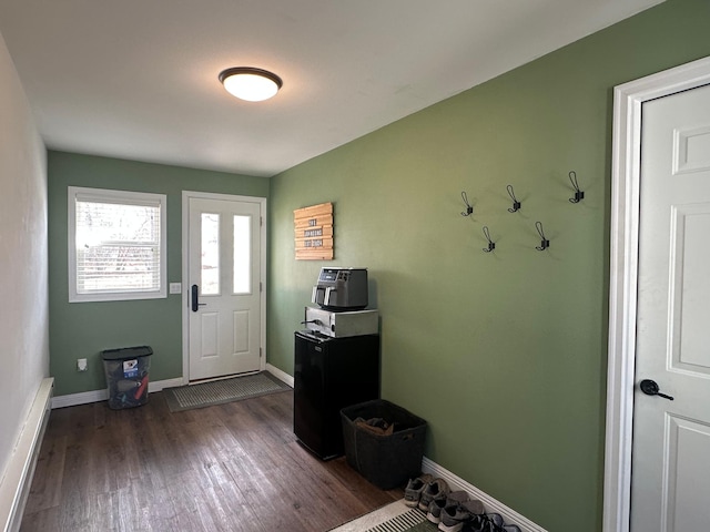 doorway featuring baseboard heating, baseboards, and wood finished floors