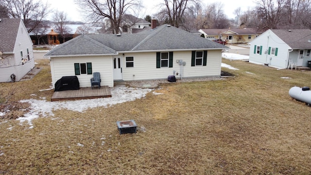 rear view of house featuring a lawn, a wooden deck, and roof with shingles