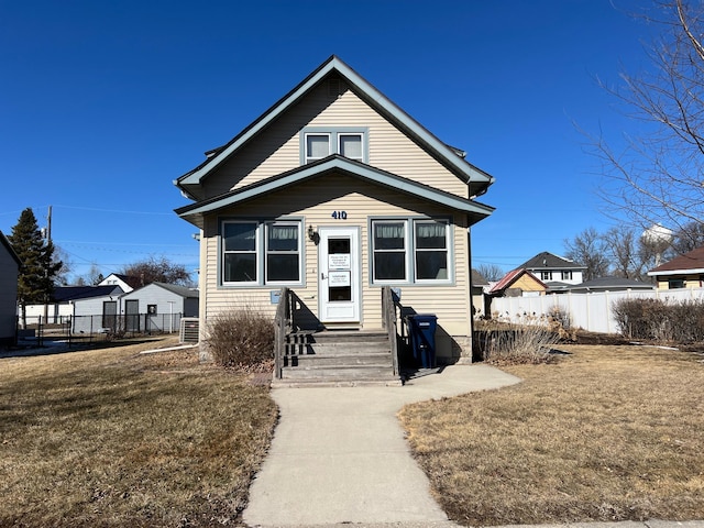 bungalow-style home with entry steps, a front lawn, and fence