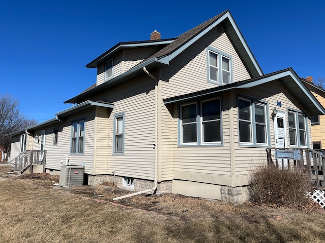 view of home's exterior featuring a chimney and central AC unit