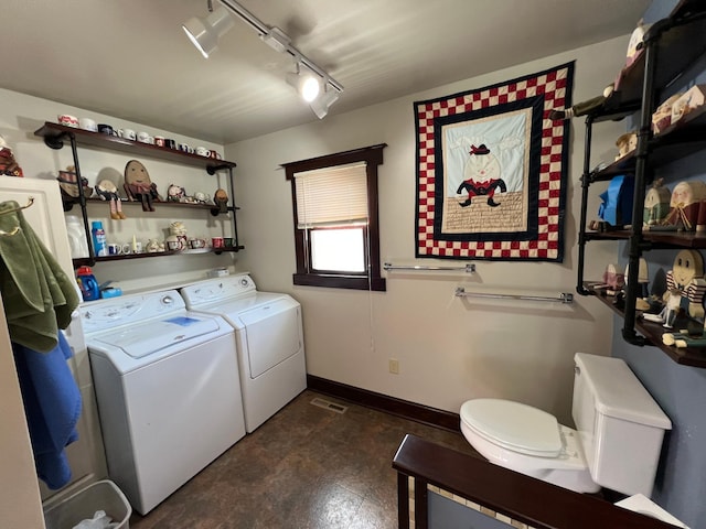 clothes washing area featuring washing machine and dryer, laundry area, visible vents, baseboards, and rail lighting