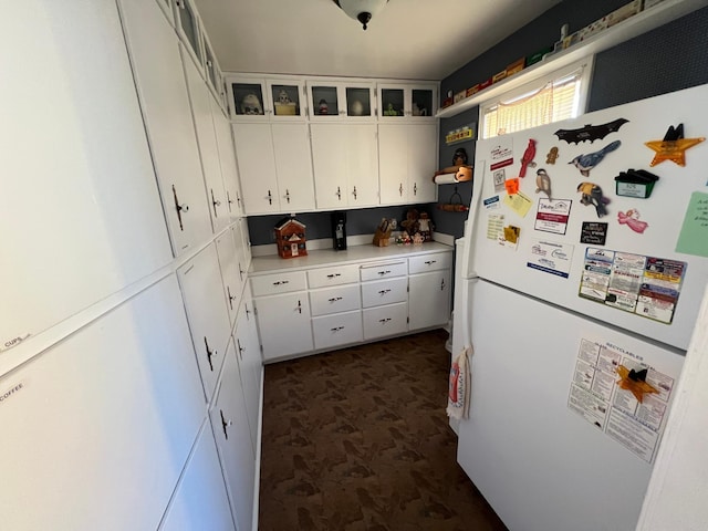 kitchen with glass insert cabinets, freestanding refrigerator, light countertops, white cabinetry, and open shelves