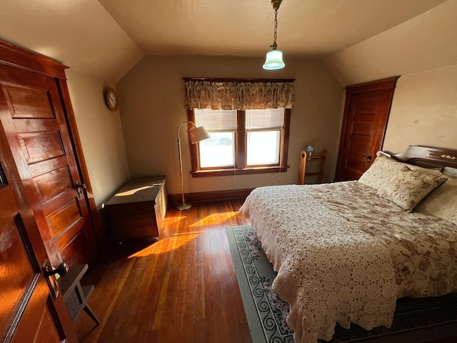 bedroom featuring lofted ceiling, baseboards, and dark wood-style flooring