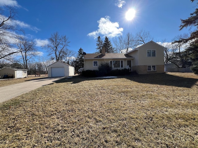 split level home with a garage, brick siding, a front lawn, and an outbuilding