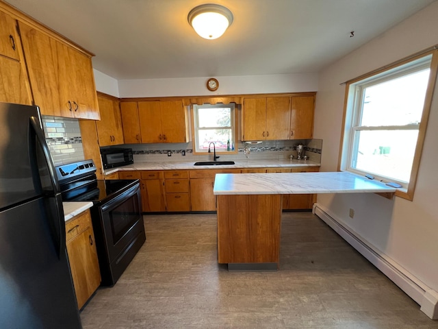 kitchen featuring a baseboard heating unit, a sink, light countertops, brown cabinets, and black appliances