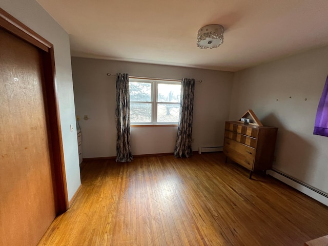 unfurnished bedroom with a baseboard radiator, light wood-style flooring, and baseboards