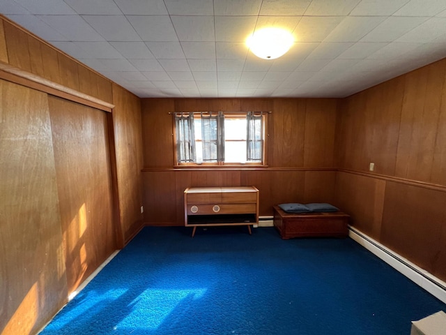 interior space featuring a baseboard heating unit, carpet, and wooden walls