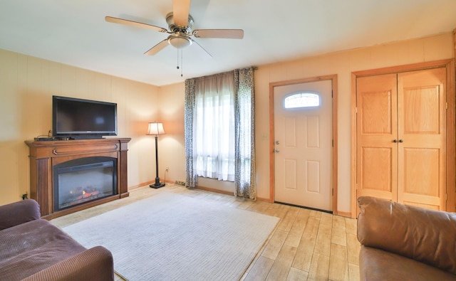 61279 US Highway 169, Hill City, MN 55748 - living area featuring baseboards, wood finished floors, a glass covered fireplace, and a ceiling fan
