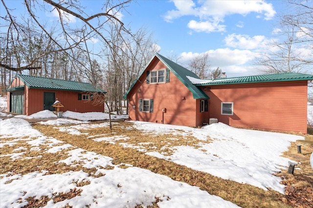 snow covered house with a garage and metal roof