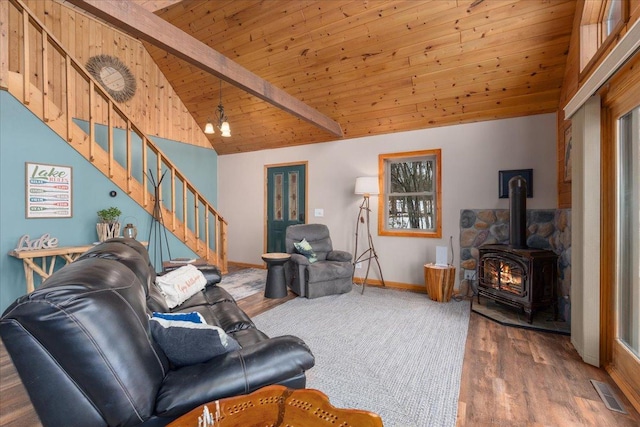 living area featuring a wood stove, wood ceiling, stairs, and beamed ceiling