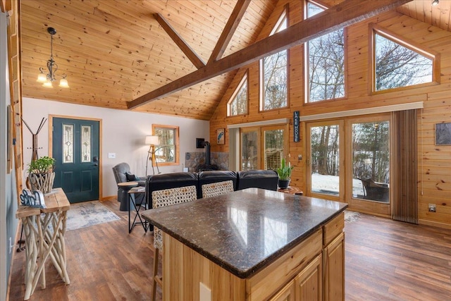 kitchen featuring a wood stove, wooden walls, dark wood finished floors, and beam ceiling