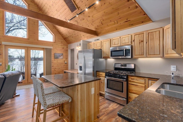 kitchen featuring wood ceiling, appliances with stainless steel finishes, wood finished floors, light brown cabinetry, and wood walls