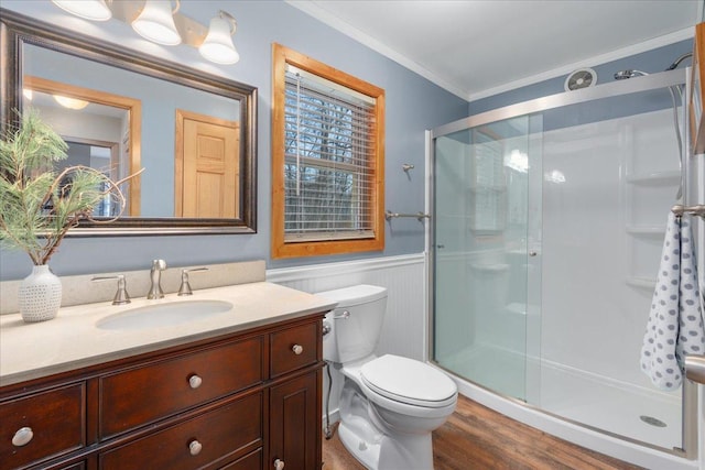 bathroom featuring a wainscoted wall, toilet, ornamental molding, a shower stall, and wood finished floors