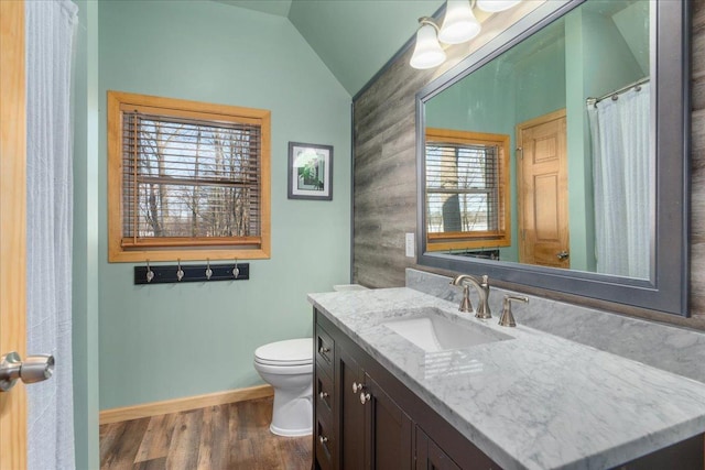 bathroom with lofted ceiling, toilet, wood finished floors, vanity, and baseboards