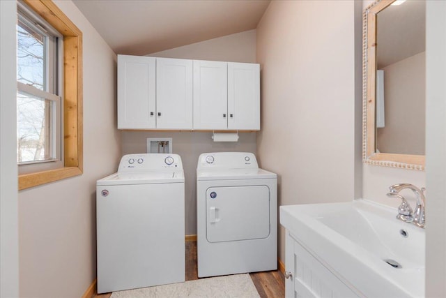 clothes washing area featuring a sink, light wood-style floors, washing machine and dryer, and a healthy amount of sunlight