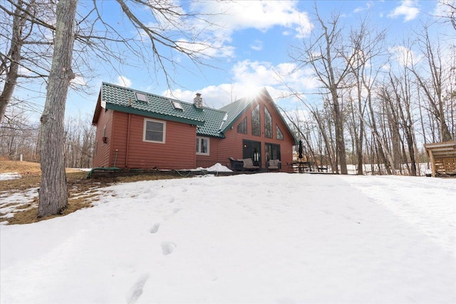 snow covered back of property with a chimney