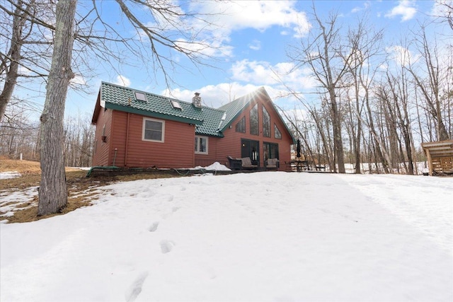 snow covered rear of property featuring a chimney