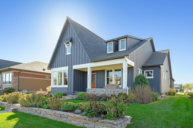 view of front of house with board and batten siding, stone siding, a shingled roof, and a front lawn