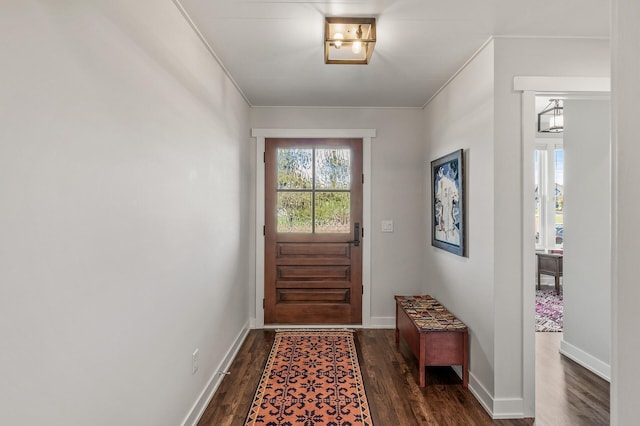 doorway to outside with crown molding, dark wood finished floors, and baseboards