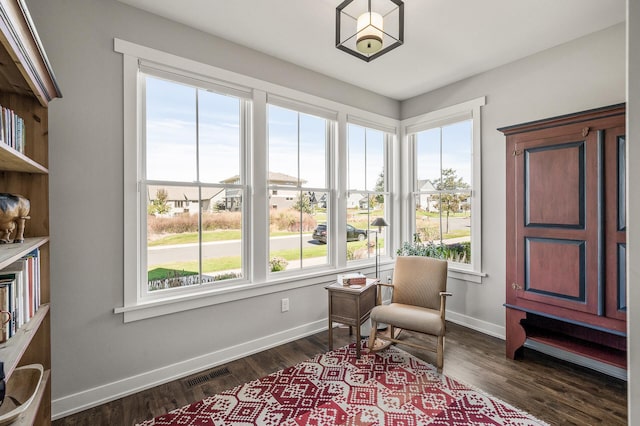 sitting room with baseboards, visible vents, and dark wood finished floors