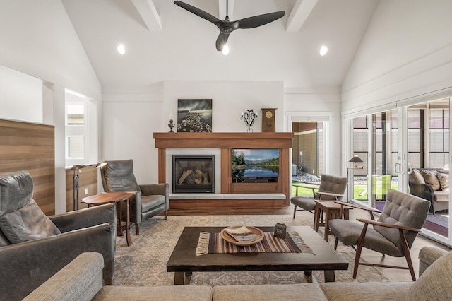 living area with high vaulted ceiling, a glass covered fireplace, beamed ceiling, and ceiling fan