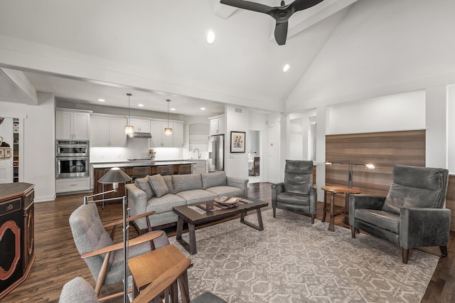 living area featuring dark wood-style floors, decorative columns, high vaulted ceiling, and a ceiling fan