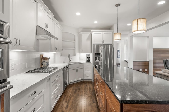 kitchen featuring under cabinet range hood, stainless steel appliances, dark wood-style flooring, a sink, and a center island