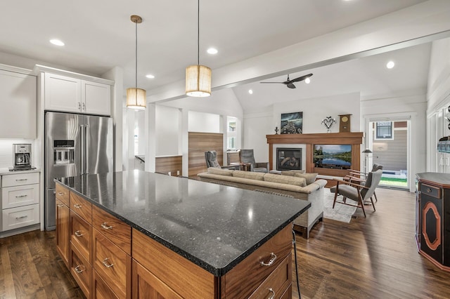 kitchen with dark wood-style floors, a center island, stainless steel fridge, and a glass covered fireplace