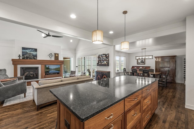 kitchen featuring brown cabinets, open floor plan, dark wood-style flooring, and a glass covered fireplace