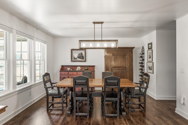 dining area featuring baseboards, dark wood-type flooring, and a notable chandelier