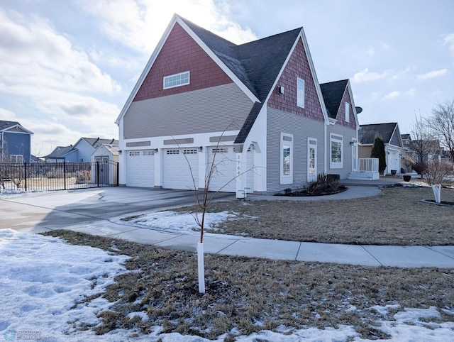 snow covered property with a gate, driveway, an attached garage, and fence