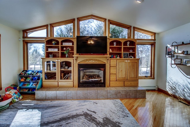 living room featuring a healthy amount of sunlight, a fireplace with raised hearth, and vaulted ceiling