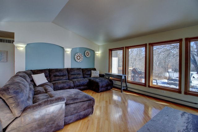 living area featuring lofted ceiling, decorative columns, light wood-style flooring, and a baseboard radiator