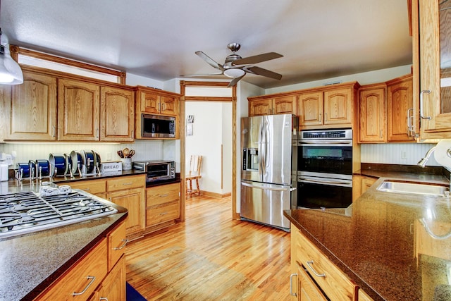 kitchen featuring a toaster, light wood finished floors, stainless steel appliances, a sink, and ceiling fan